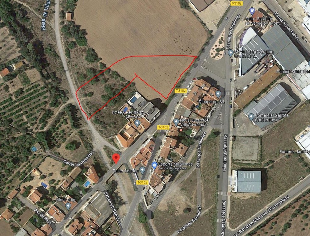 Aerial view of a vacant lot outlined in red, adjacent to residential and commercial buildings. Roads and vegetation surround the property. [AI-generated text]