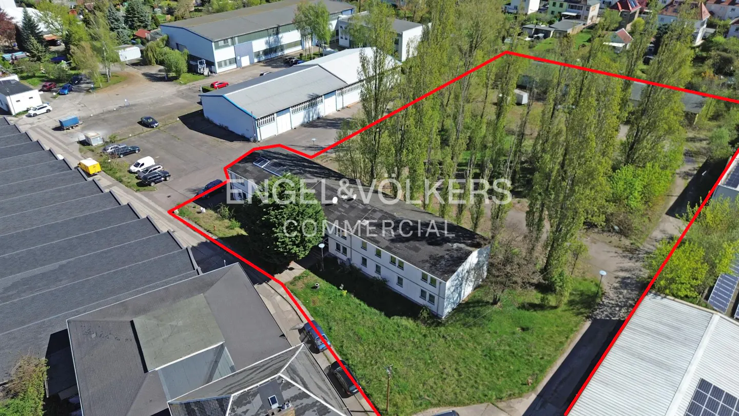 Aerial view of a commercial property outlined in red, featuring a two-story building, parking lot, and trees.