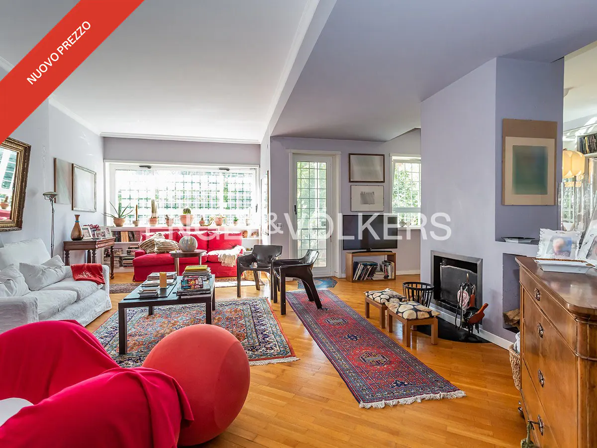 Bright living room with hardwood floors, red and white sofas, area rugs, and a fireplace. "Nuovo Prezzo" banner in the corner.