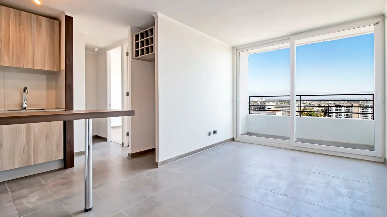 Bright apartment interior with wood cabinets, a breakfast bar, and a sliding glass door to a balcony with a city view.