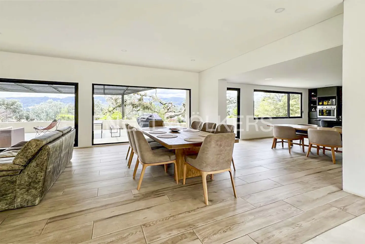 Open-concept living space with wood-look tile, a dining table with eight chairs, and a view of the outdoors.