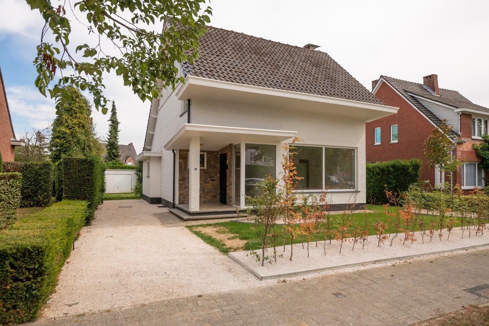 Modern white house with a stone entryway, gravel driveway, and small front garden on a suburban street. [AI-generated text]