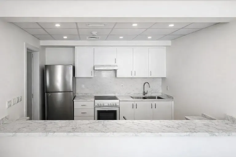 Bright, modern kitchen with white cabinets, stainless steel appliances, and marble countertops.