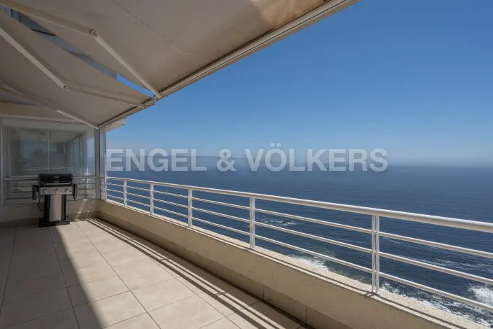 Balcony with a grill and ocean view. White railings line the balcony, with a retractable awning above. Engel & Völkers logo is visible.