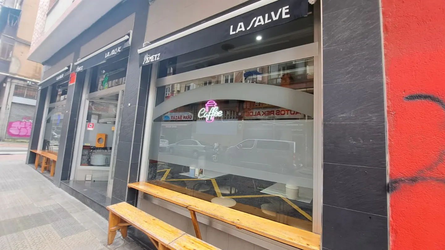 Exterior view of "La Salve" coffee shop with black awning, frosted windows, and wooden benches outside.