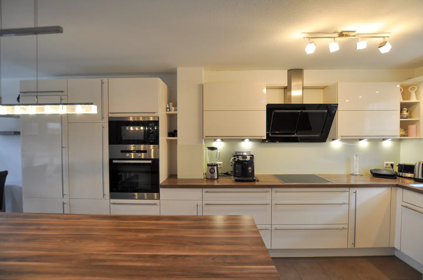 Modern kitchen with white cabinets, wood countertops, stainless steel appliances, and a large wooden kitchen island.