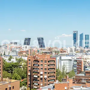 Elevated view of a Madrid cityscape featuring the iconic leaning KIO towers under a clear blue sky.