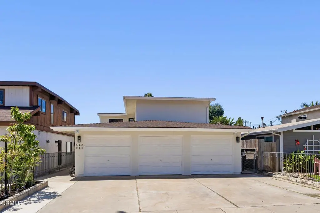 A three-car garage with white doors and a brown roof under a clear blue sky.