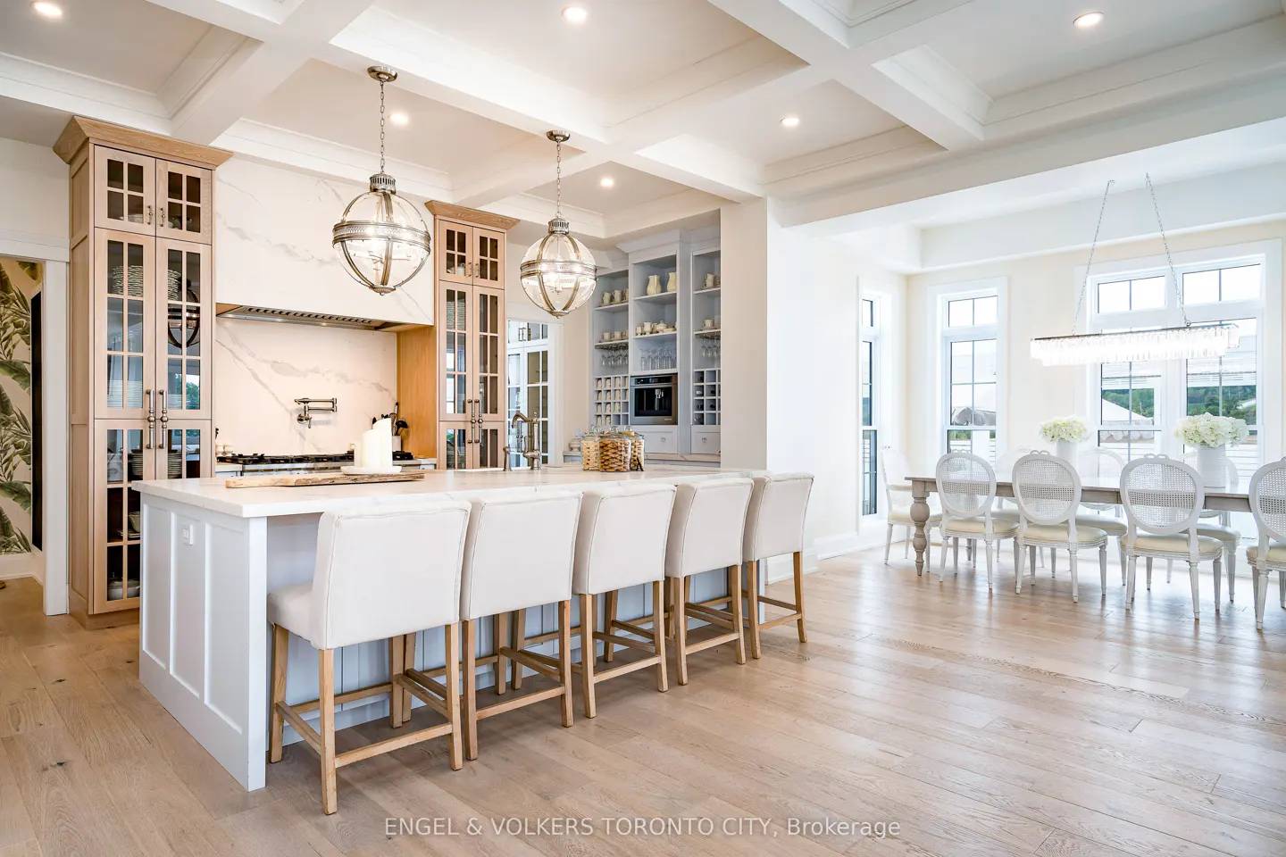 A bright, open kitchen with a large island and seating, next to a dining area with a long table.