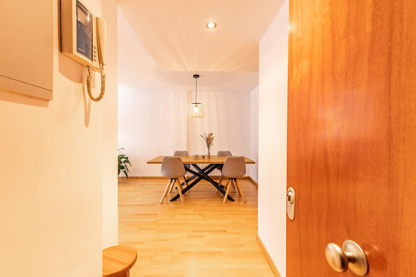View from doorway into a dining room with a wooden table, four chairs, and a hanging light fixture.