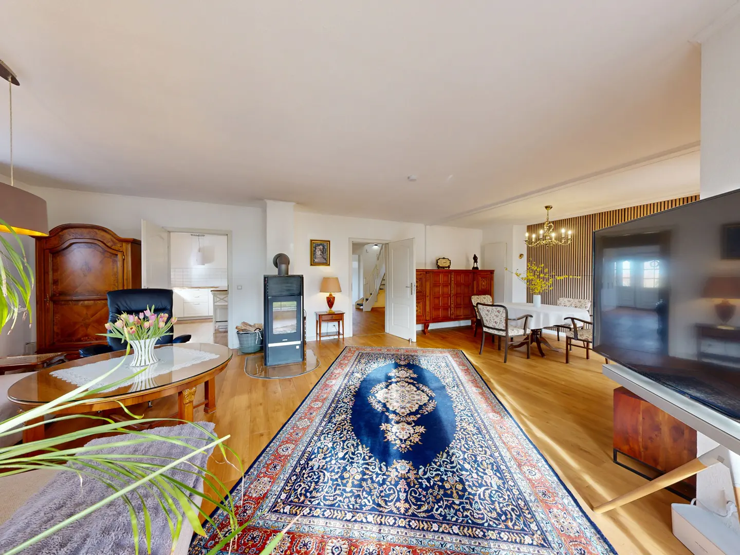 A spacious living room with wood floors, a blue rug, a fireplace, and a dining area.