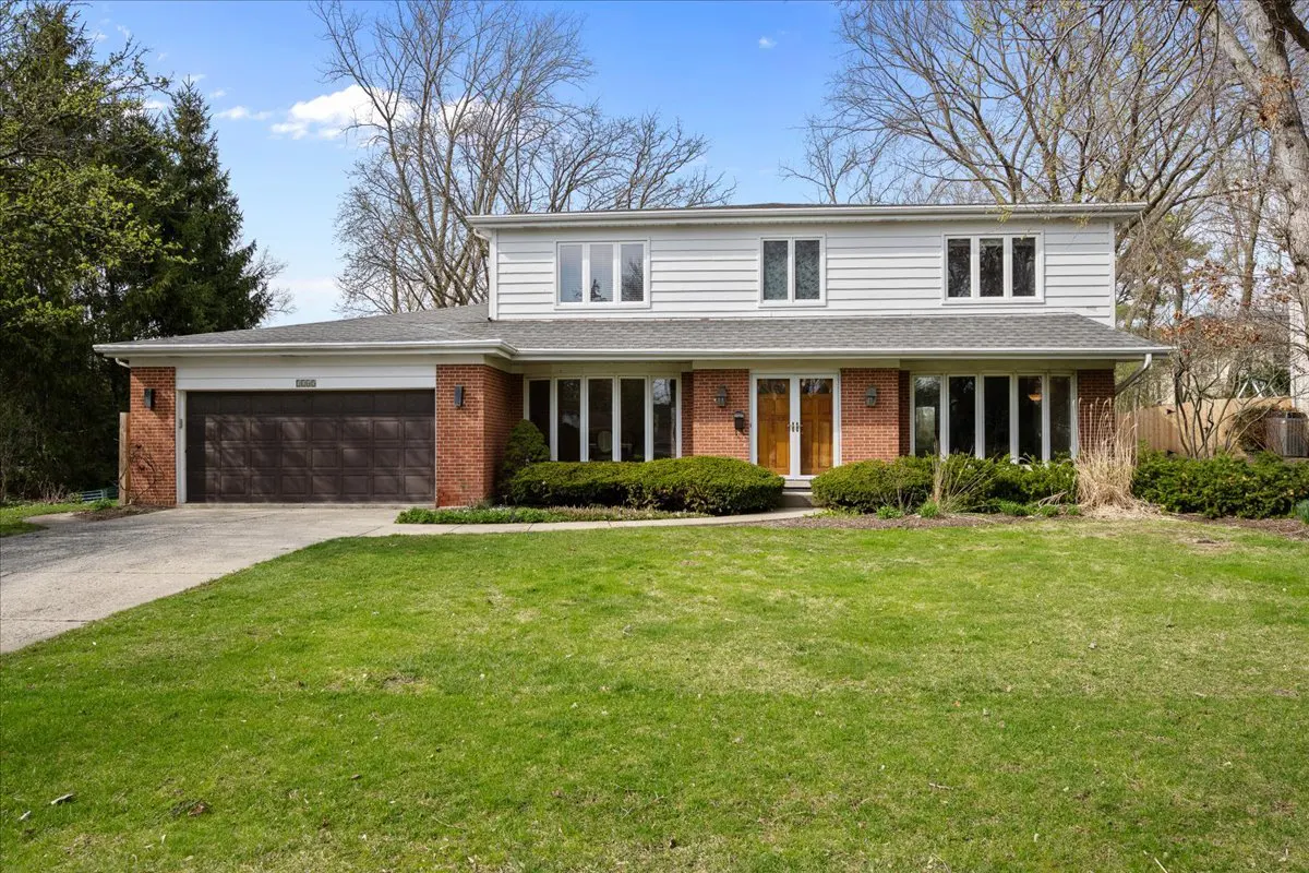 Two-story house with a brick and white siding exterior, a brown garage door, and a green lawn.
