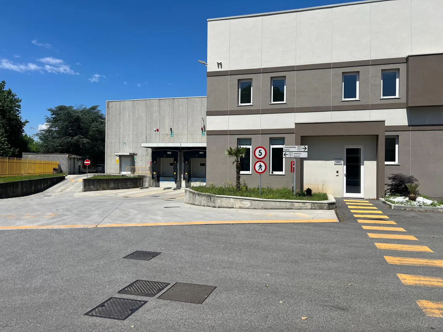 Exterior view of a two-story commercial building with loading docks and a pedestrian crosswalk.