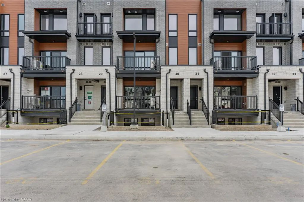 Row of modern townhouses with brick and wood facade, black balconies, and parking spaces.