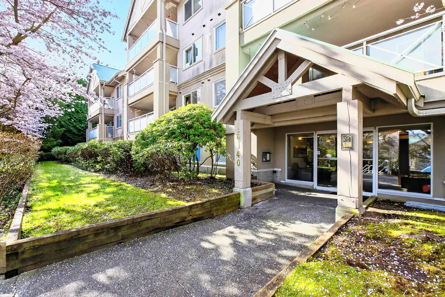 Exterior view of a multi-story apartment building with a covered entrance and landscaped grounds.
