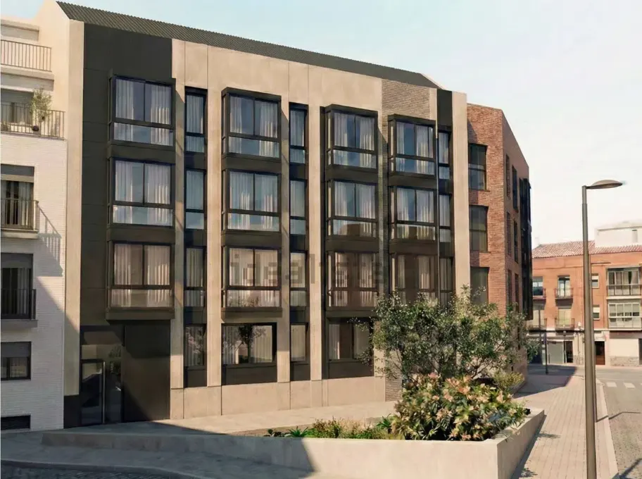 Modern apartment building with large windows, a beige facade, and a dark gray accent wall. A street lamp stands nearby.