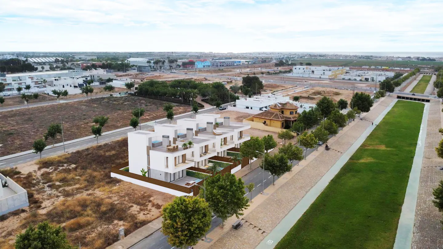 Aerial view of modern, white townhouses with small pools and patios, set in a developing urban area with green spaces.