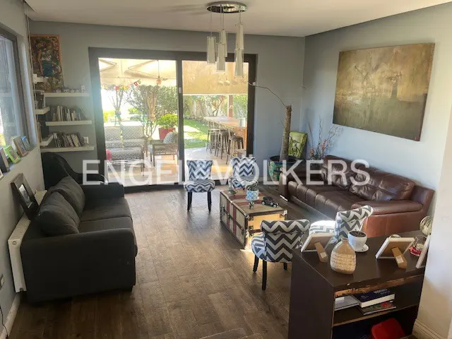Living room with dark wood floors, gray walls, and a large sliding glass door to a patio. Furnished with sofas, chairs, and a trunk-style coffee table.