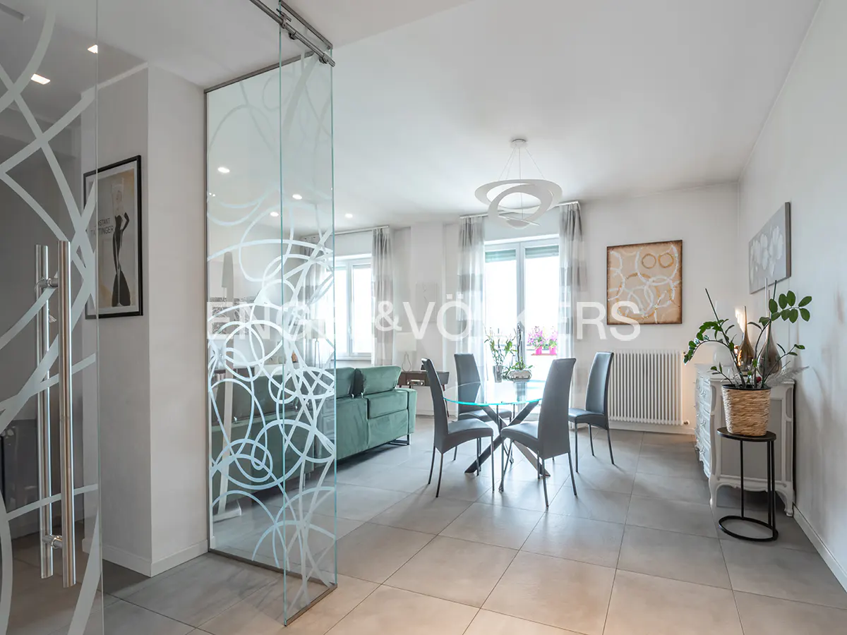 Living room with glass sliding doors featuring a white swirl design, a dining table with gray chairs, and a green sofa.