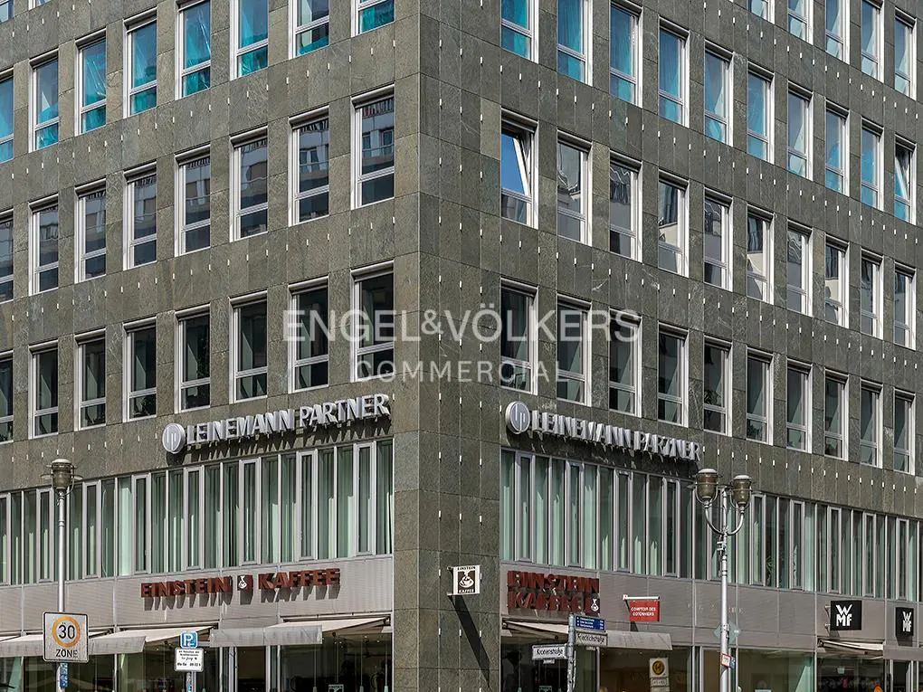 Exterior of a gray stone building with many windows. "Engel & Völkers Commercial" and "Leinemann Partner" are displayed on the building.
