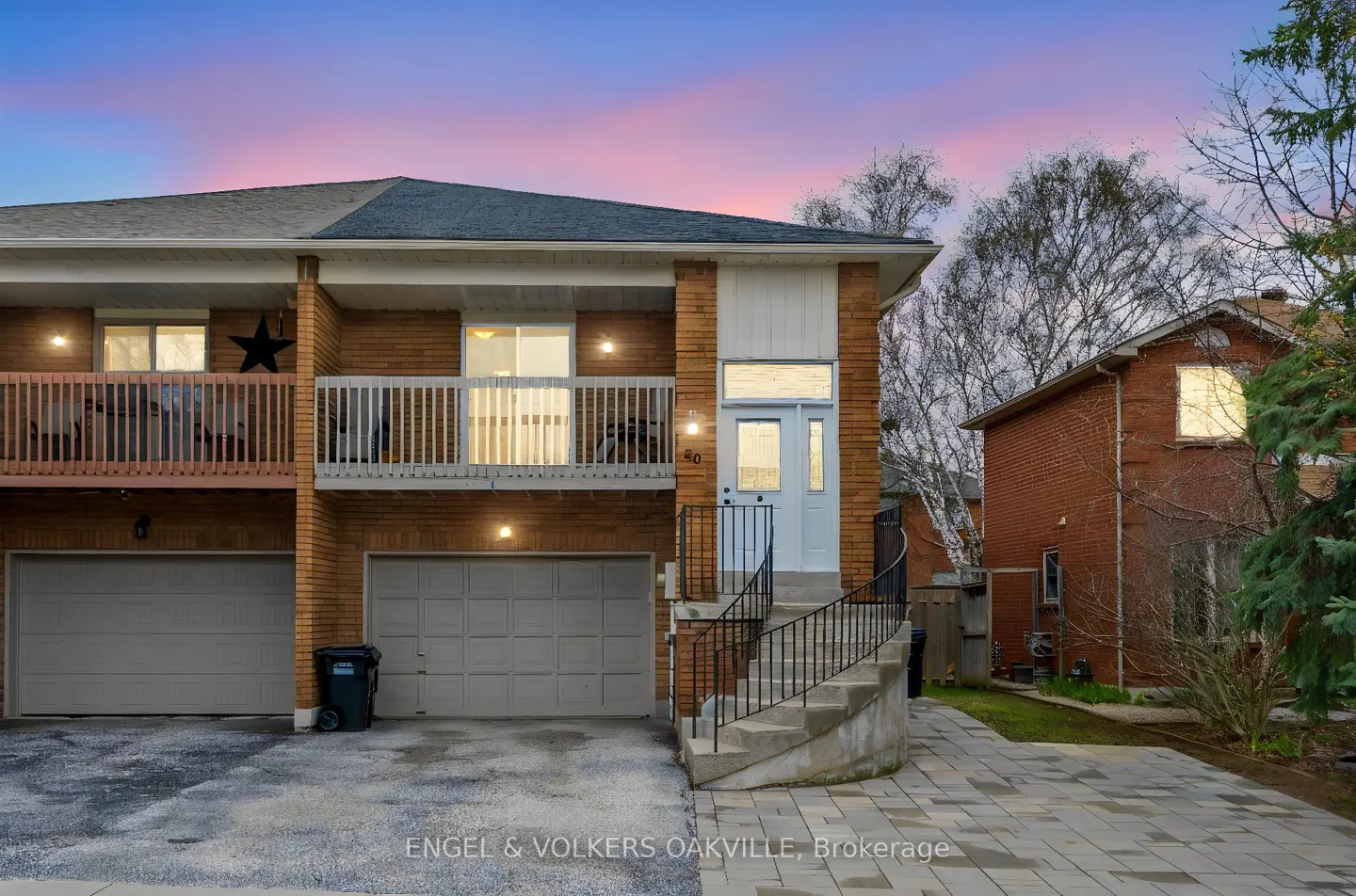 Exterior view of a two-story brick townhouse with a light blue door and a balcony under a pink and blue sky.