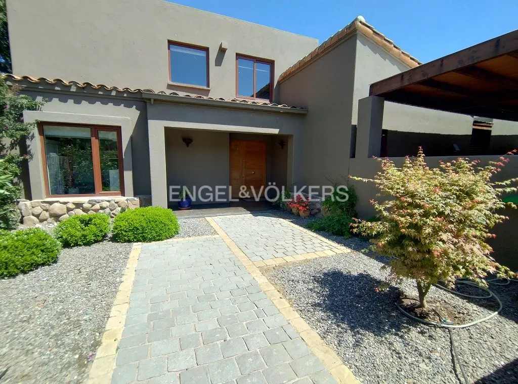 Exterior of a two-story gray house with a stone walkway, green bushes, and an Engel & Völkers sign.
