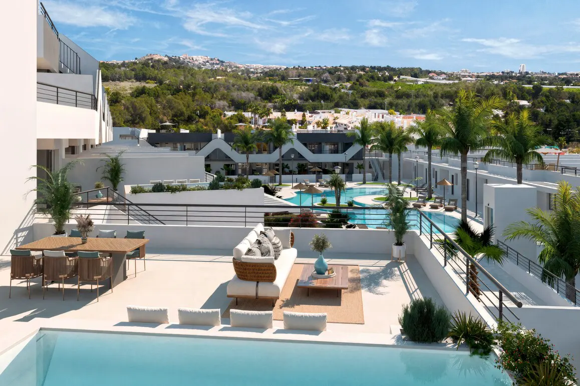 Luxury apartment complex with a pool, outdoor seating, and palm trees under a blue sky.