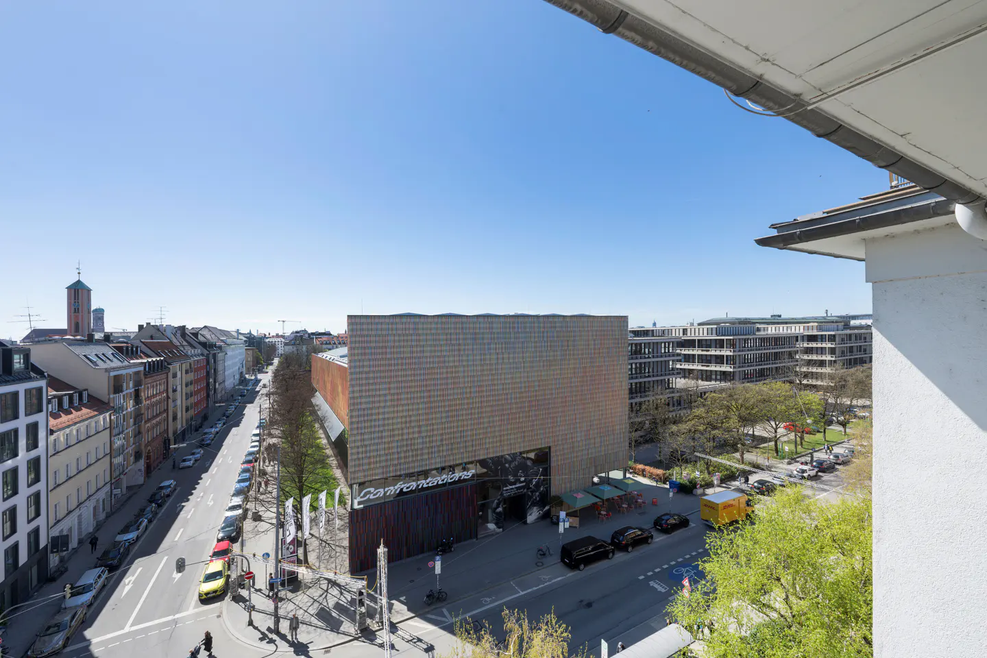 View from a high angle of a city street with cars, buildings, and a blue sky.