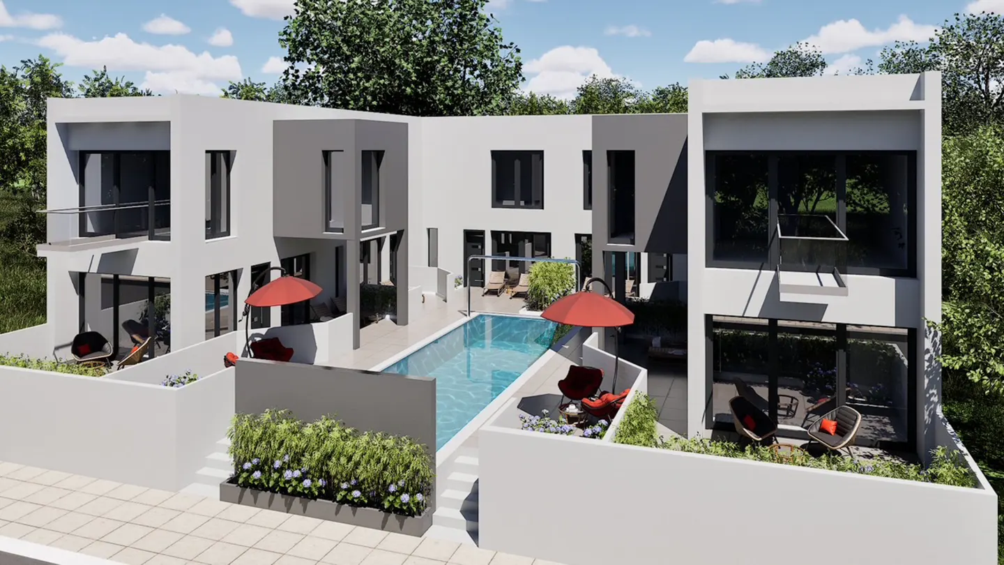 Modern white building with a pool. Red umbrellas and chairs surround the pool. Trees are in the background.