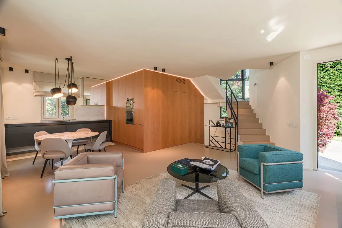 Open-concept living space with a kitchen, dining area, and lounge. Features include wood cabinetry, modern furniture, and a staircase.