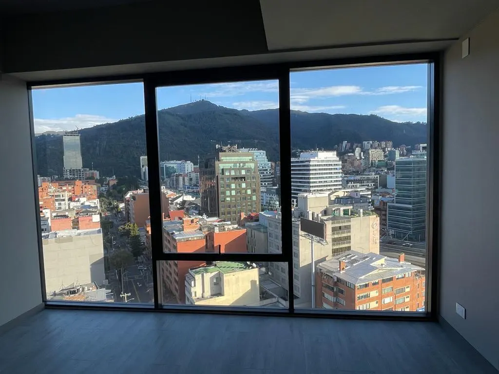 View from a modern apartment with a large window overlooking a city skyline and mountain.