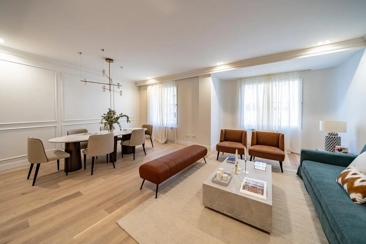 Bright living room with a dining area, featuring a marble table, brown chairs, a blue sofa, and a marble coffee table.