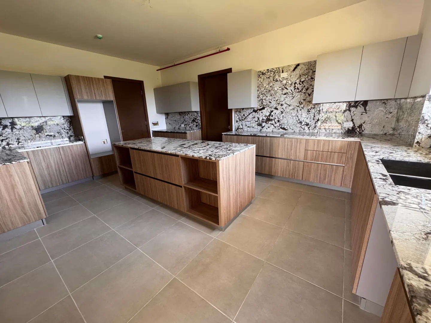 A modern kitchen with wood cabinets, granite countertops, and a central island with open shelving.