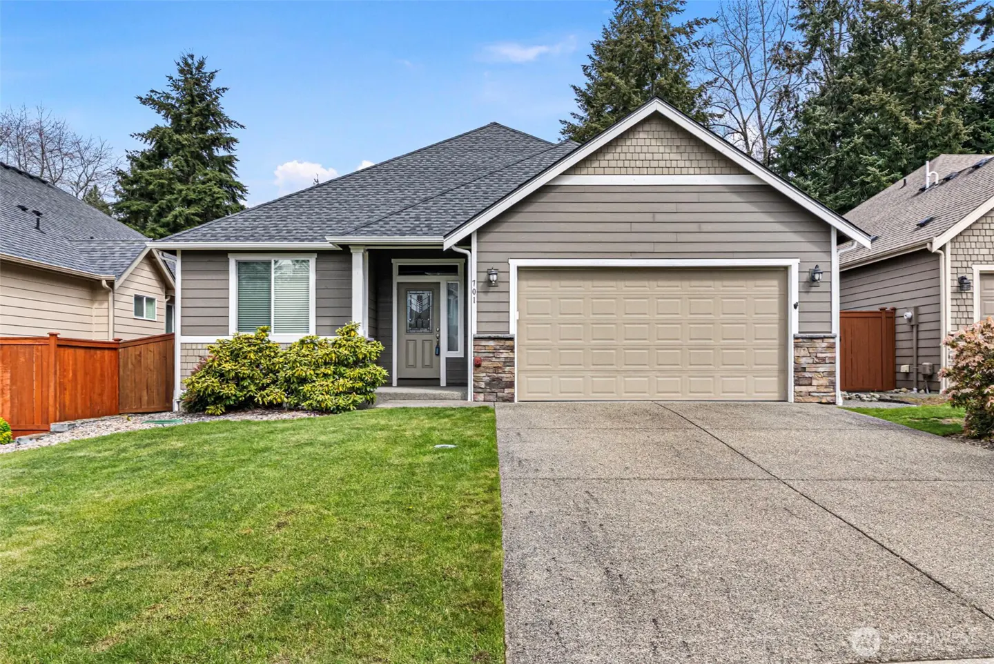 A single-story home with gray siding, a beige garage door, and a gray roof on a sunny day.