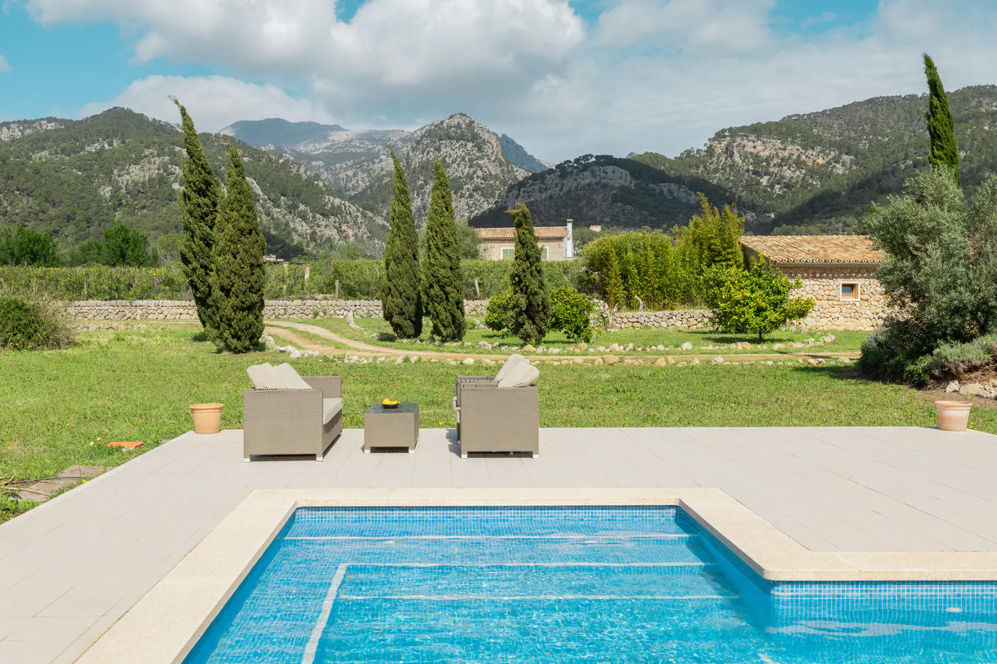 Outdoor patio with blue tiled pool, tan seating, and mountain views.