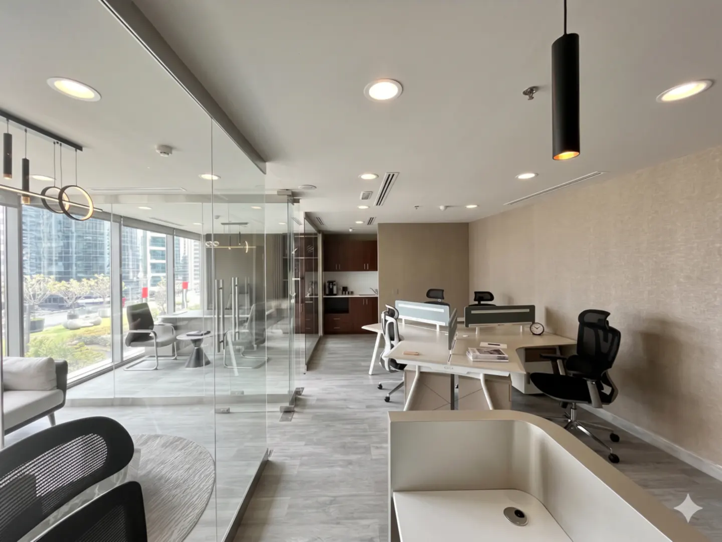 Bright office space with desks, chairs, and a glass-walled conference room. Neutral colors, modern lighting, and city views.