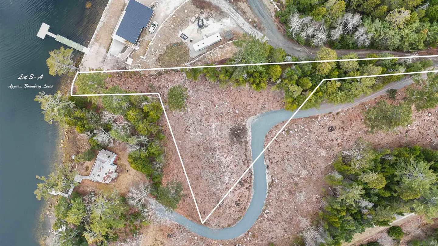 Aerial view of Lot 3-A, a waterfront property with a dock, outlined in white. A winding road cuts through the wooded area.
