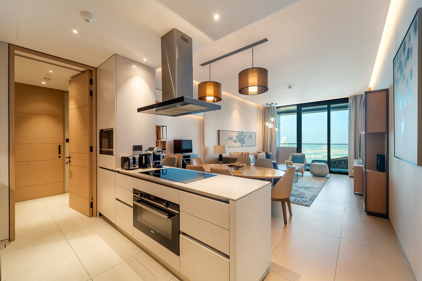 A modern apartment interior with a kitchen island, dining area, and living room. Large windows offer a city view. Neutral color palette.
