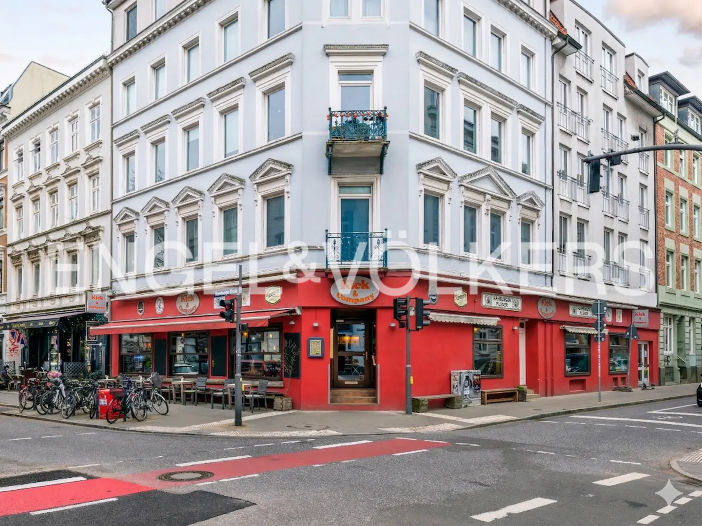 Street view of a corner building with a red restaurant on the ground floor and apartments above. Bicycles parked outside.