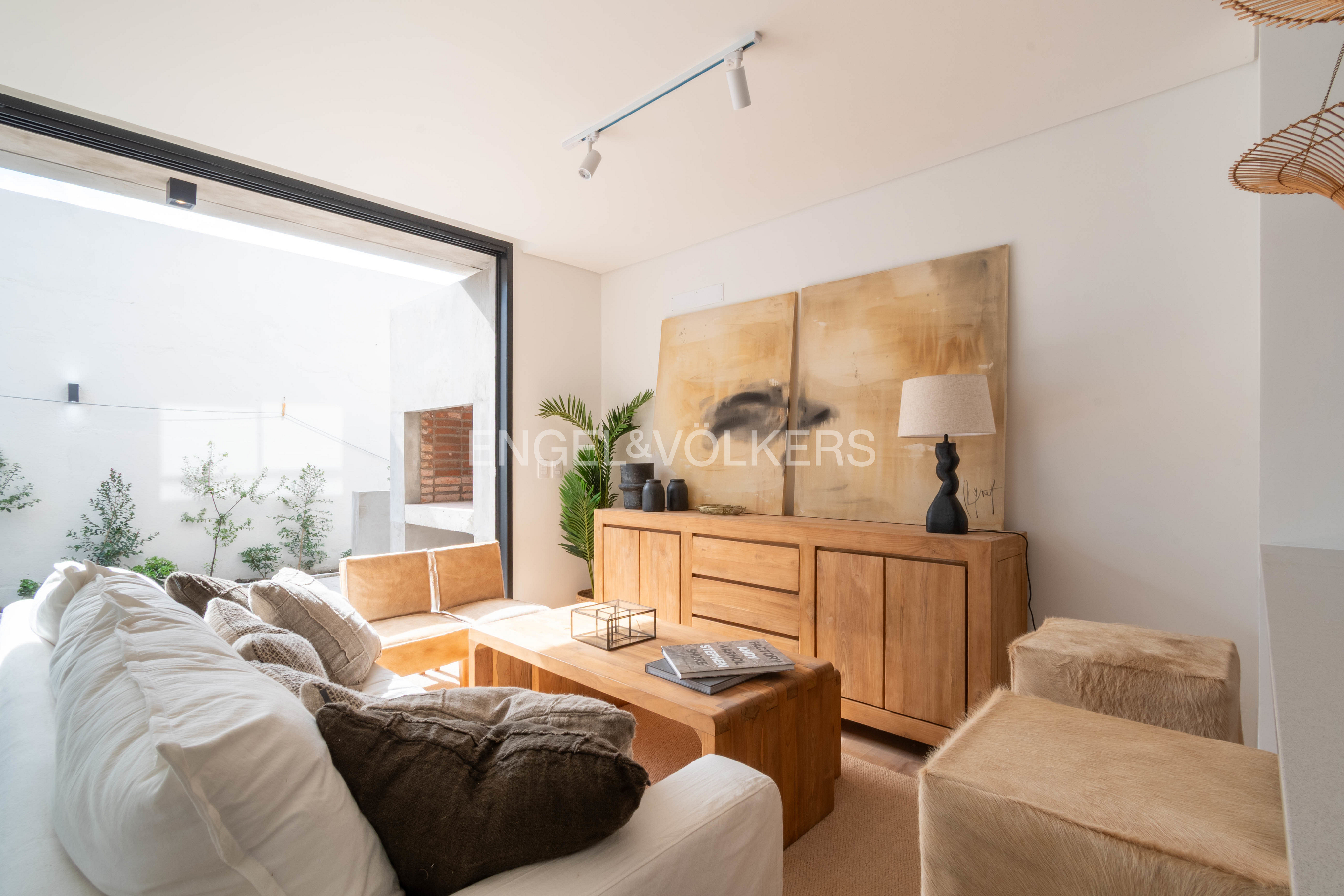 Modern living room with white sofa, wooden sideboard, abstract art, and large sliding doors opening to a patio. [AI-generated text]