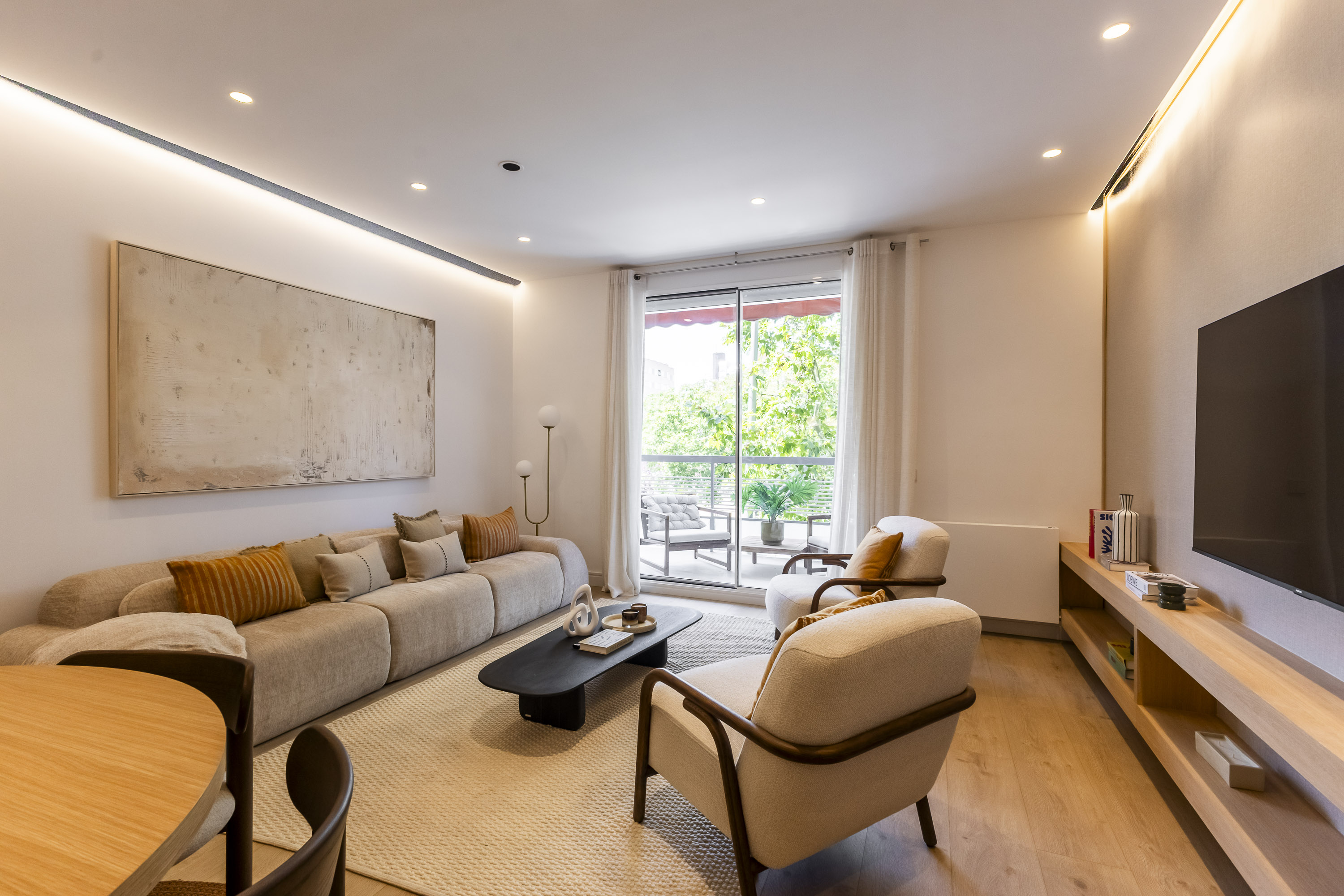Modern living room with beige sofa, two armchairs, black coffee table, large abstract art, and balcony access.
