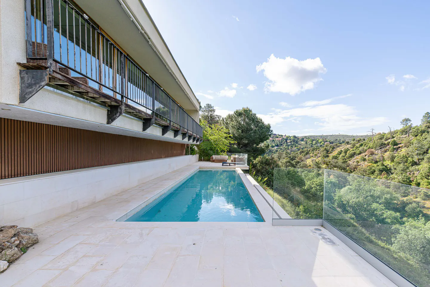 Exterior view of a modern house with a pool and a view of the green hills.