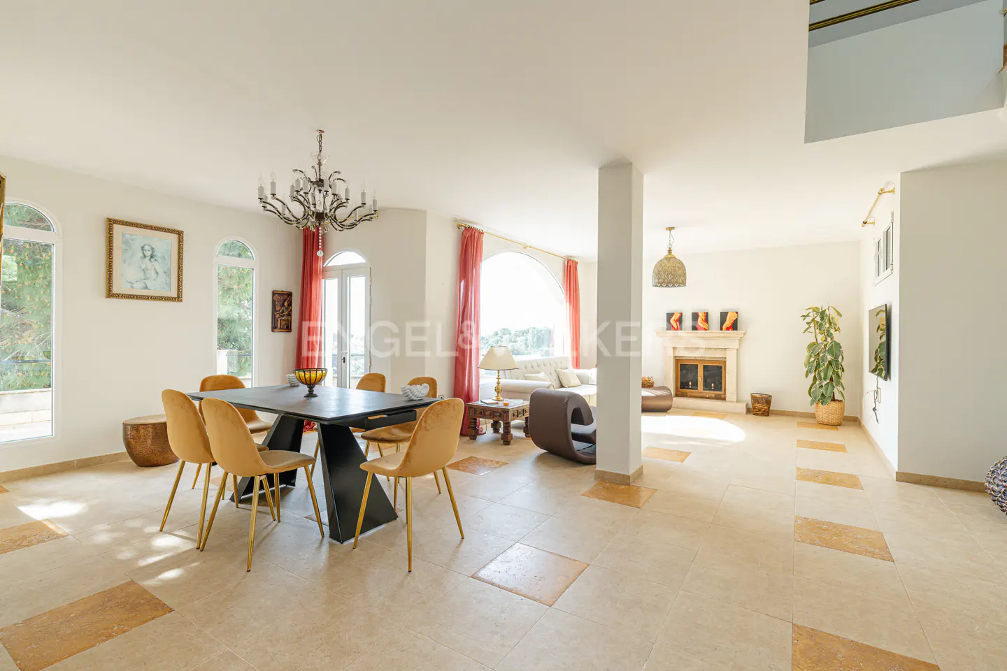 Open-concept living and dining area with a black table, yellow chairs, and a chandelier. A fireplace and seating area are in the background.