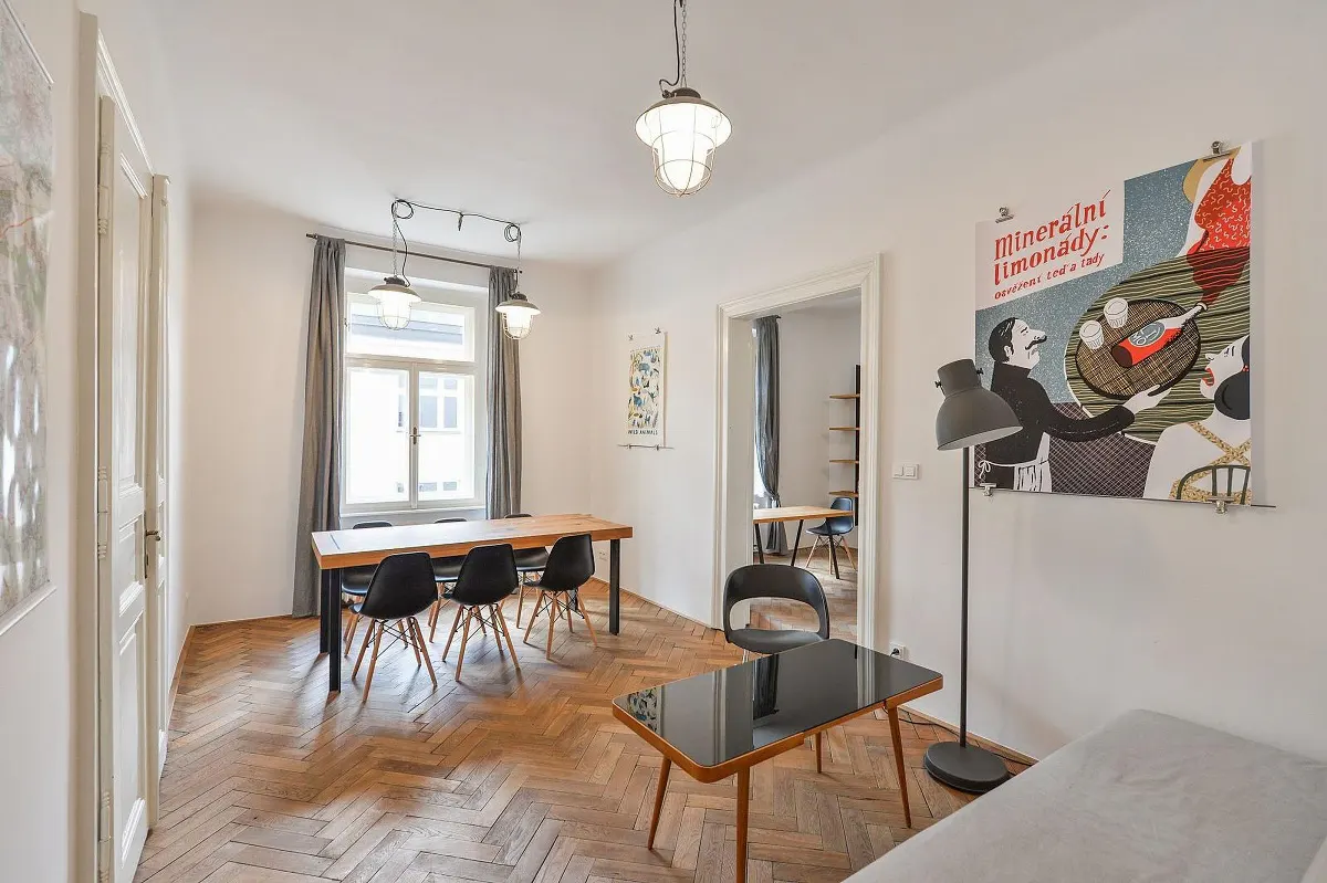 Bright room with herringbone wood floors, a dining table with black chairs, and a vintage poster on the wall.