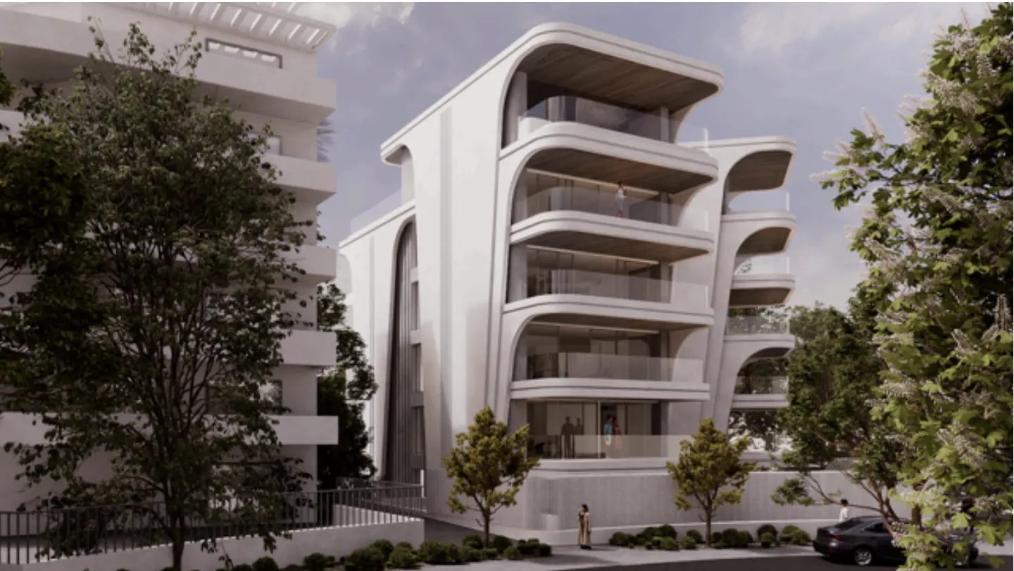 Modern white apartment building with curved balconies and glass railings, surrounded by trees and greenery.