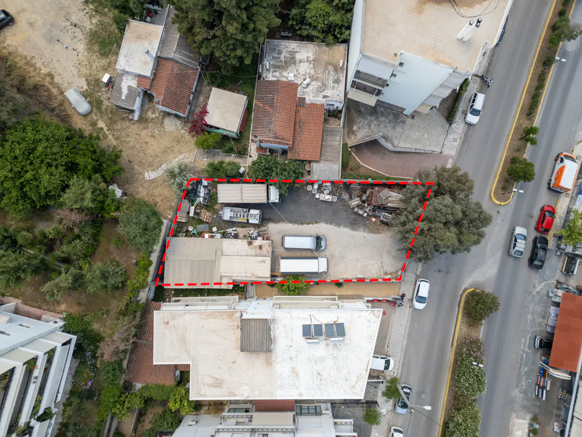 Aerial view of a property outlined in red, with trucks, buildings, and a street nearby.