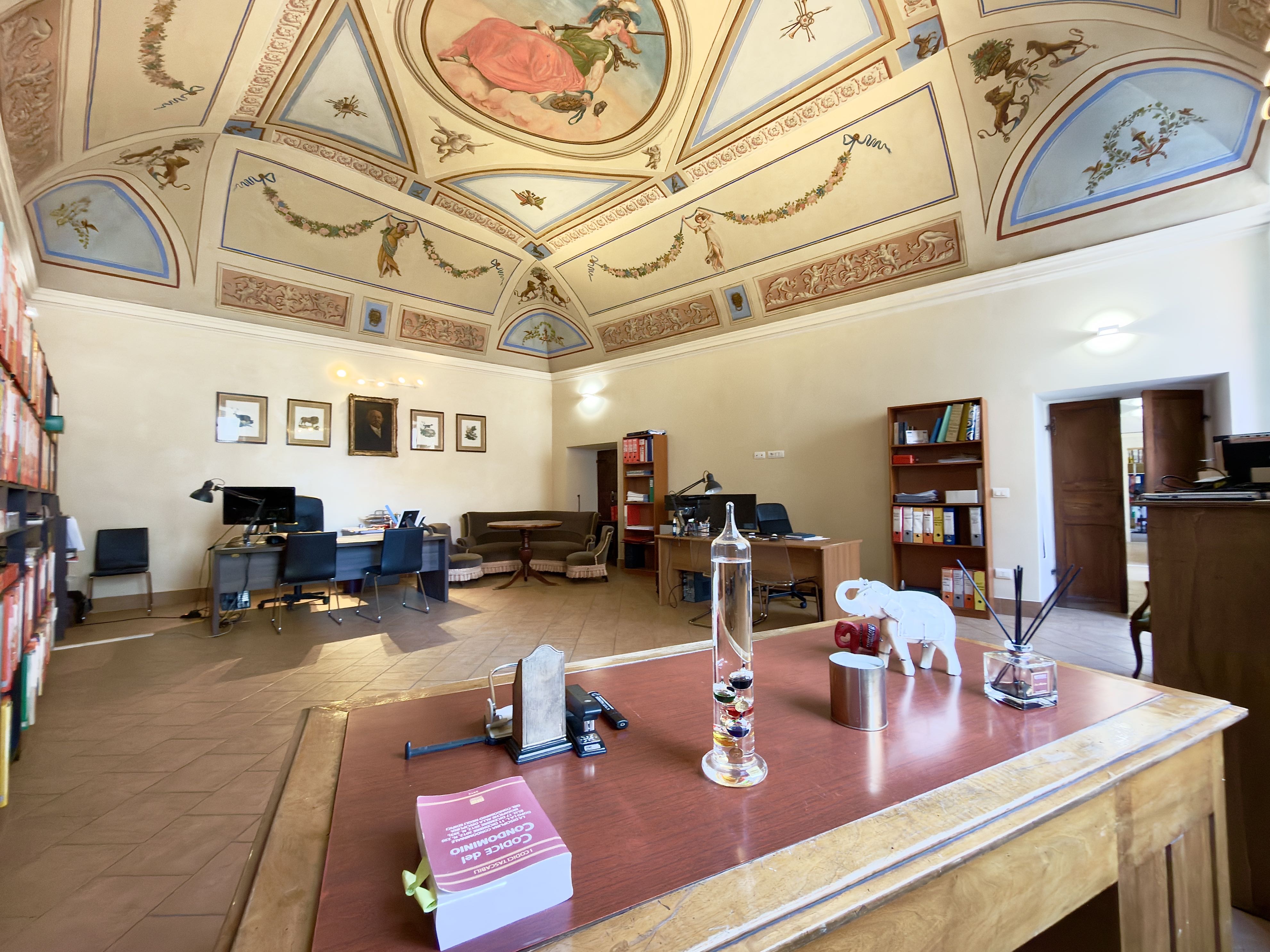 Spacious office with a painted vaulted ceiling, wooden desks, bookshelves, and a decorative elephant figurine on a desk.