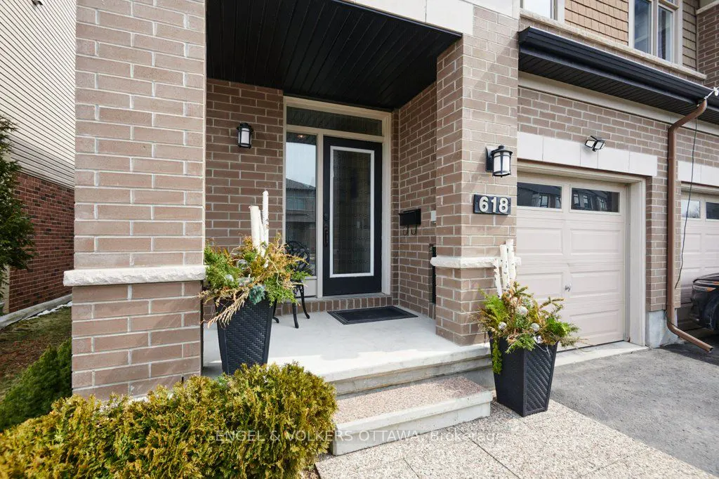 Exterior of a brick townhouse with a black front door, address number 618, and a beige garage door.