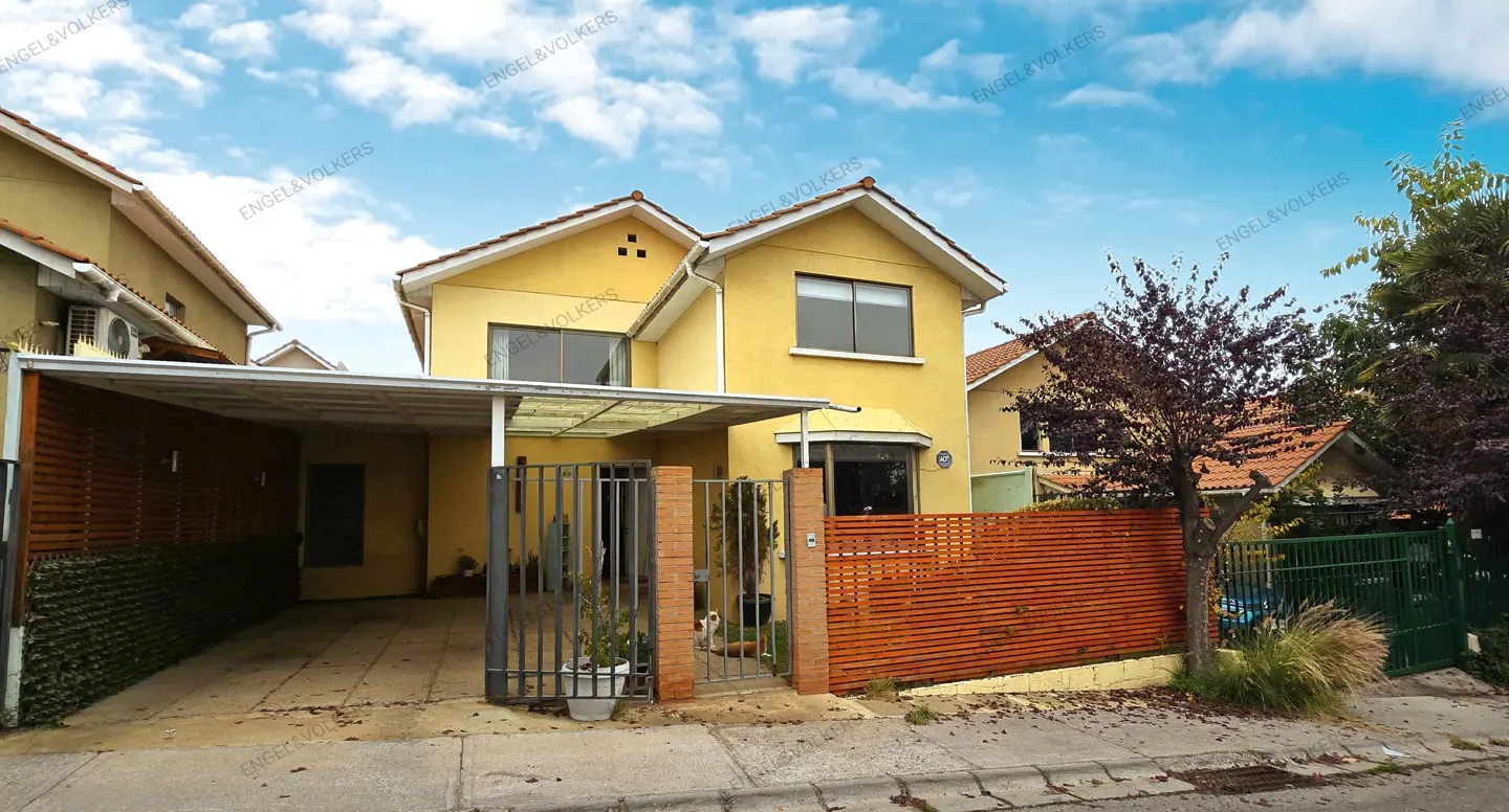 Two-story yellow house with a carport, metal gate, and a brown wooden fence.