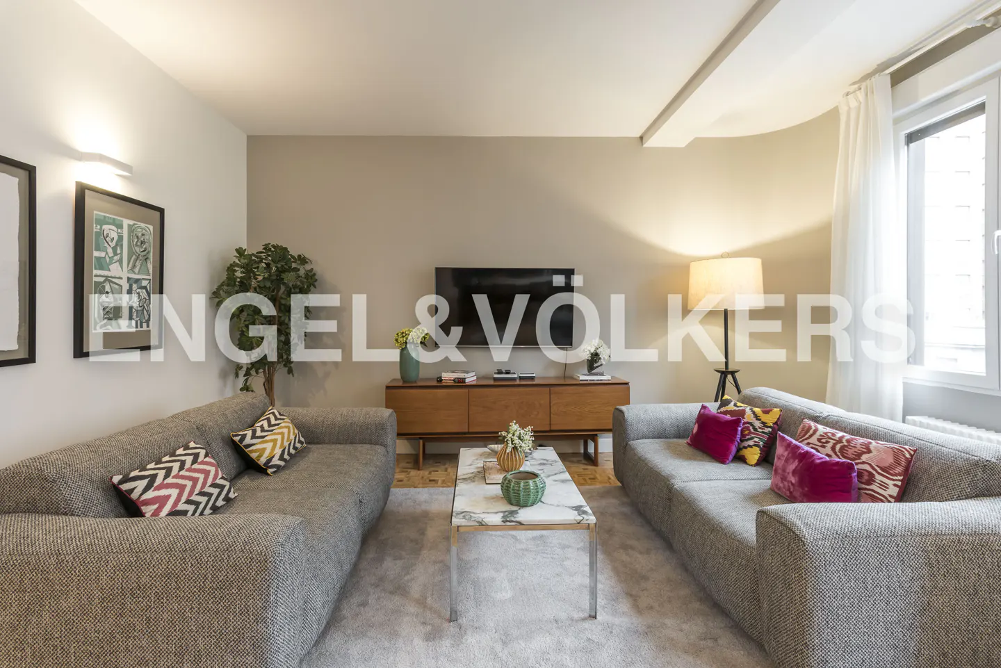 Modern living room with two grey sofas, a marble coffee table, a wooden media console, and a wall-mounted TV.